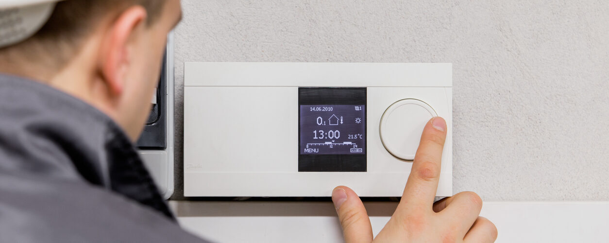 Engineer adjusting thermostat for efficient automated heating system.