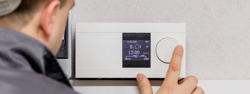 Engineer adjusting thermostat Engineer adjusting thermostat for efficient automated heating system.